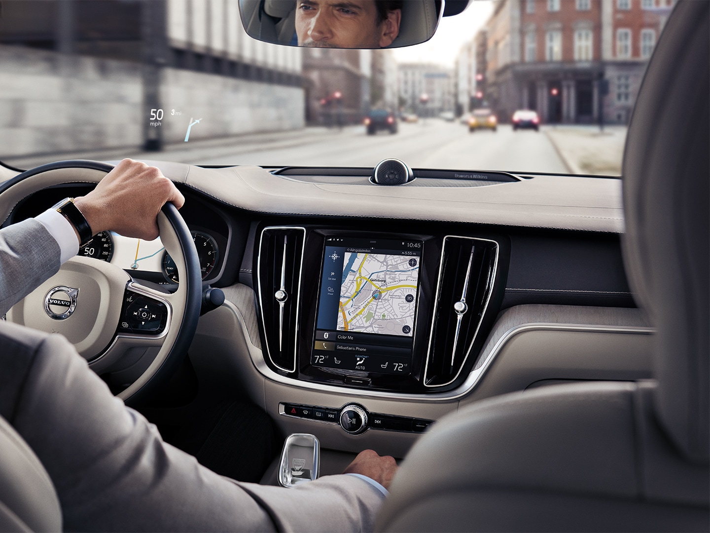 Inside a Volvo Sedan, a man driving on the road with help of navigation system
