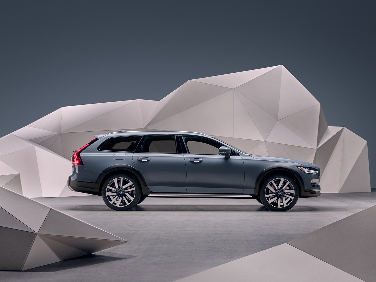 A mussel blue metallic Volvo Estate V90 standing in front of an artistic wall