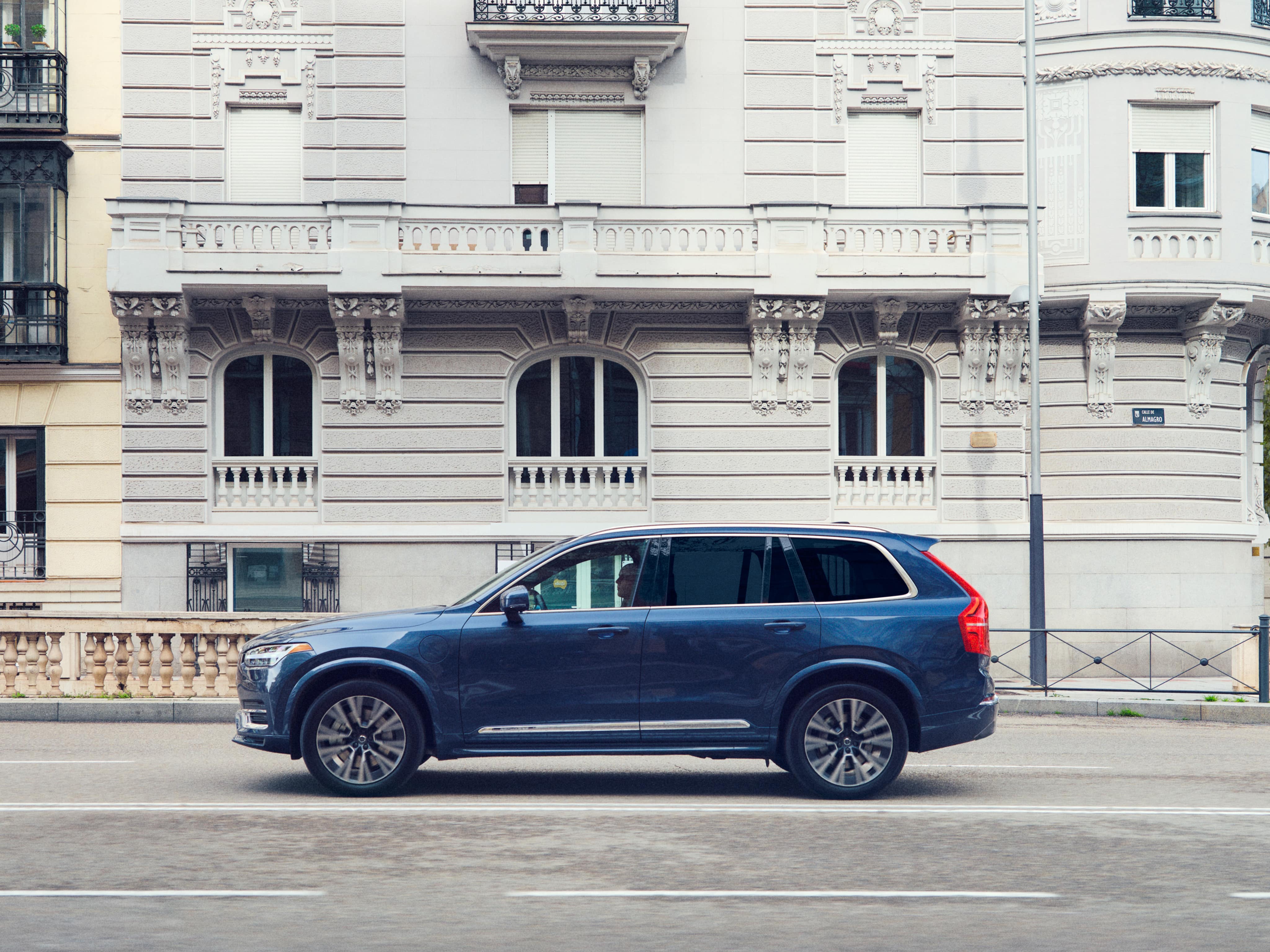 A Volvo XC90 Recharge plug-in hybrid parked in front of a building.