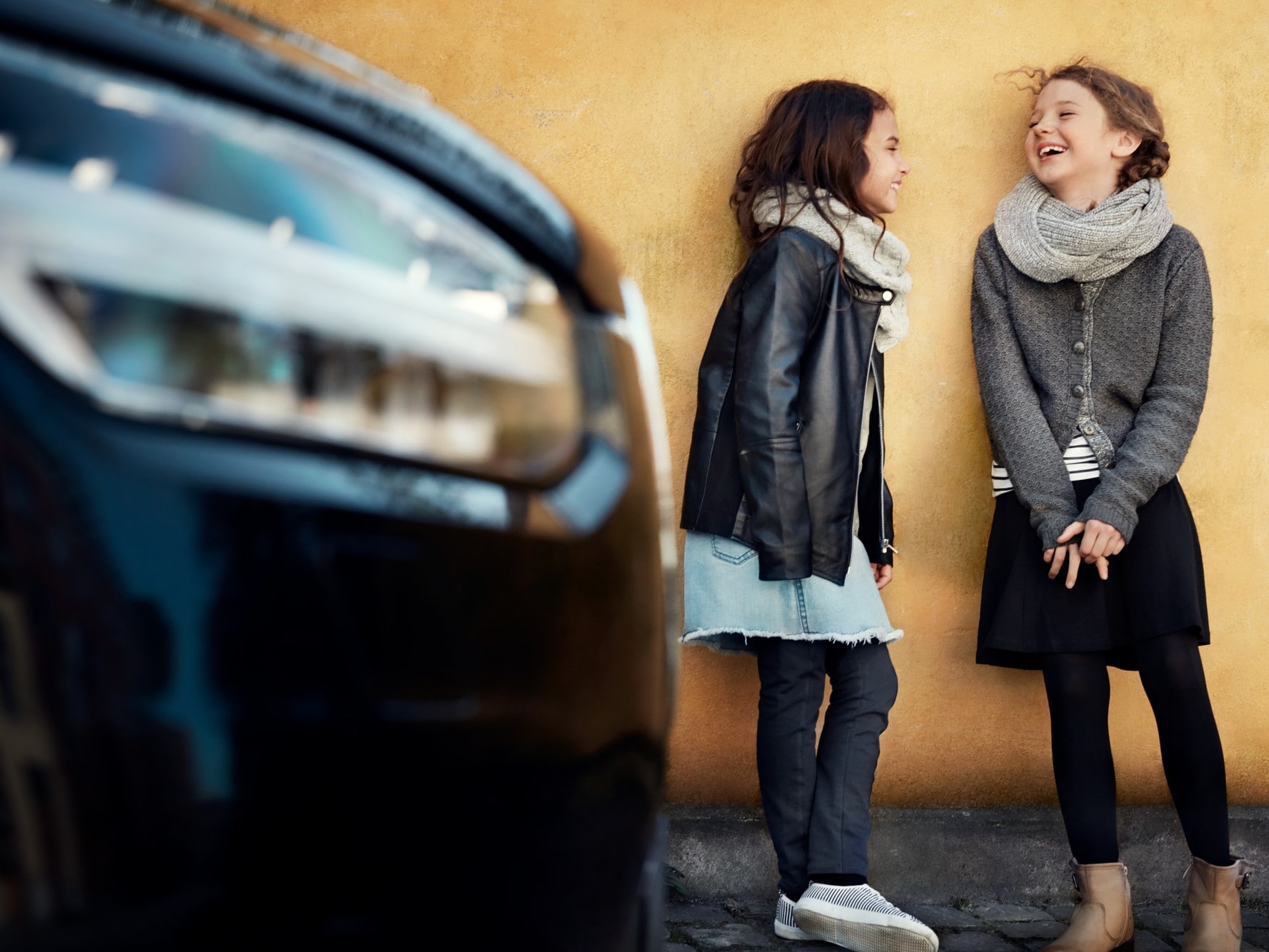 Bir Volvo'nun yanında duran iki kız çocuğu
