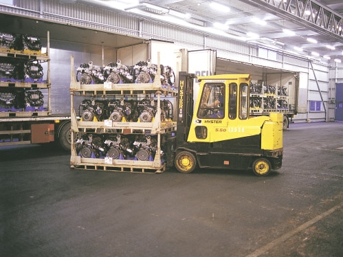 Yellow forklift is moving pallets with car parts.