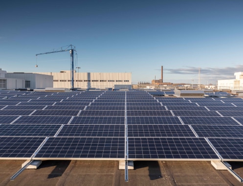 Grand nombre de cellules solaires devant le bâtiment d'une usine.