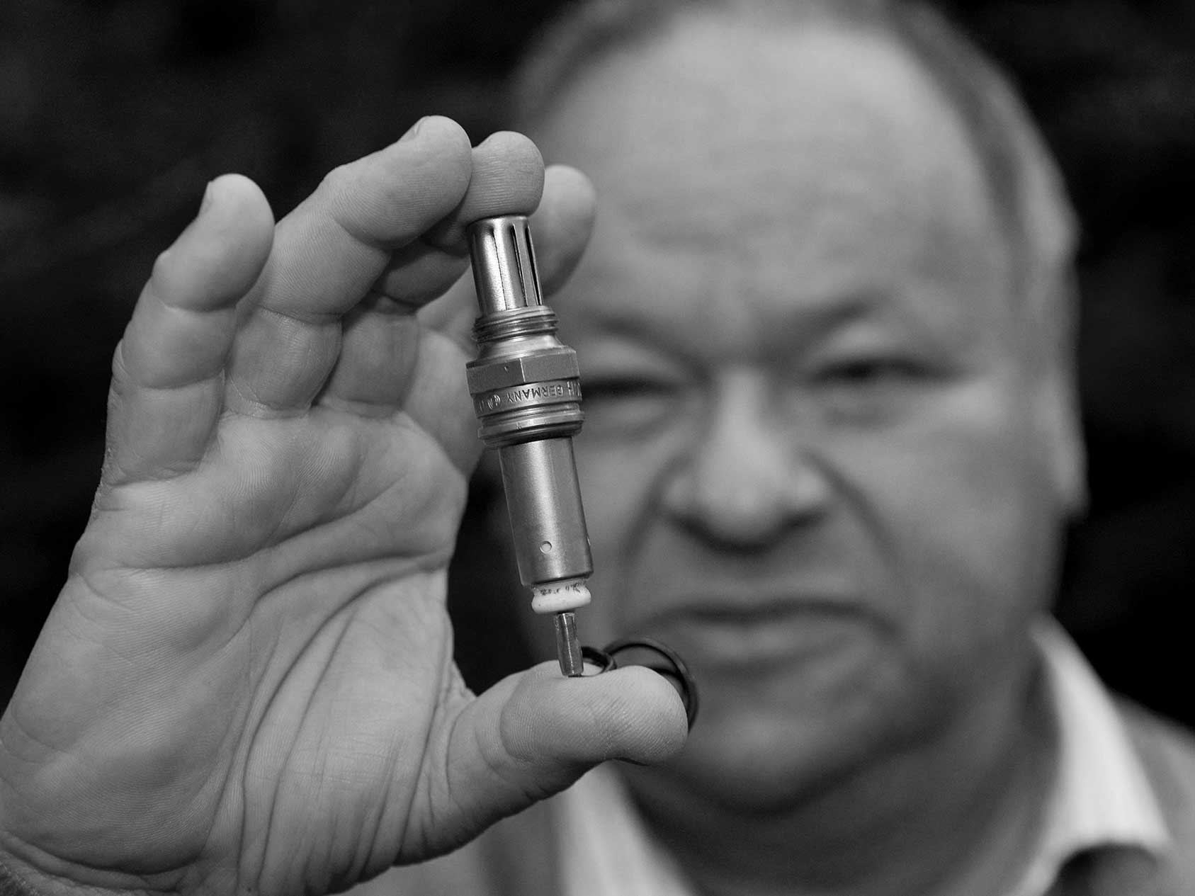 An elderly gentleman shown holding a spark plug.