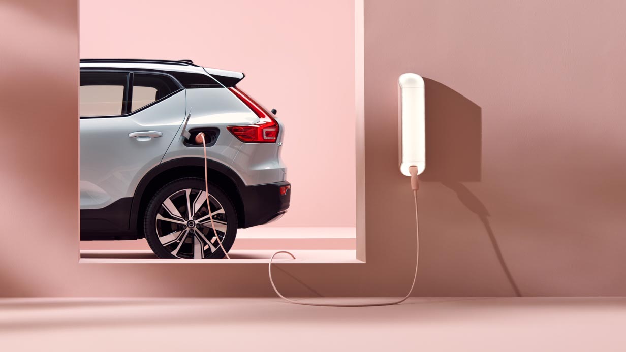 A silver Volvo XC40 Recharge electric SUV charging in a pink surrounding.