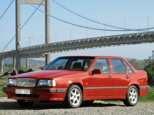 A red Volvo 850 standing in front of a bridge.