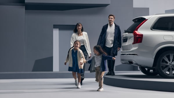 A family with 2 kids walking past a Volvo XC90