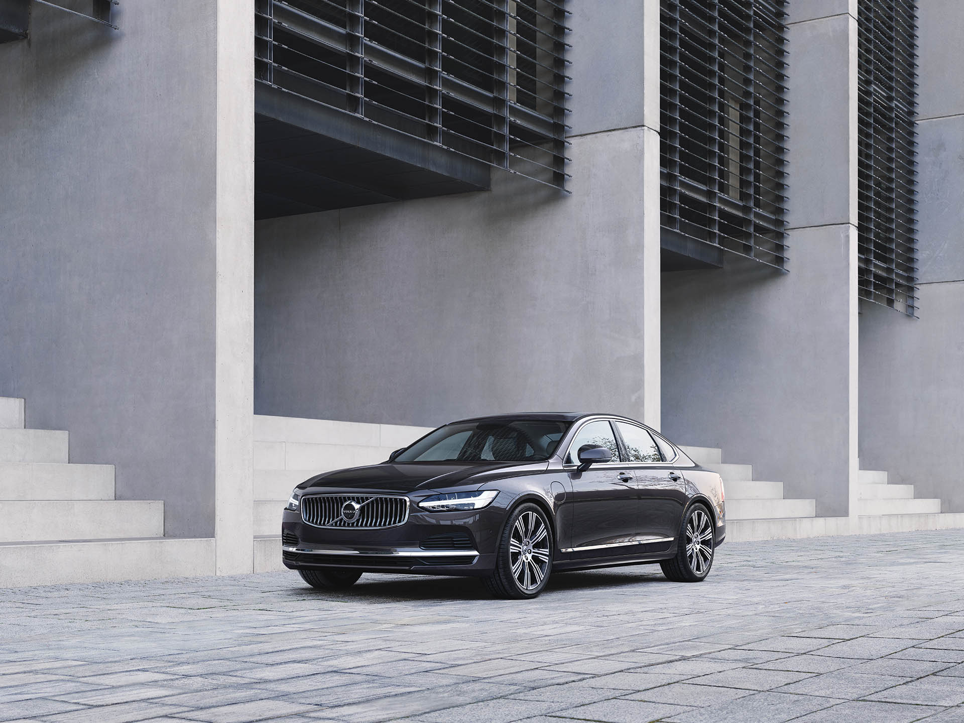 A dark grey Volvo S90 Recharge pure electric parked outside a building