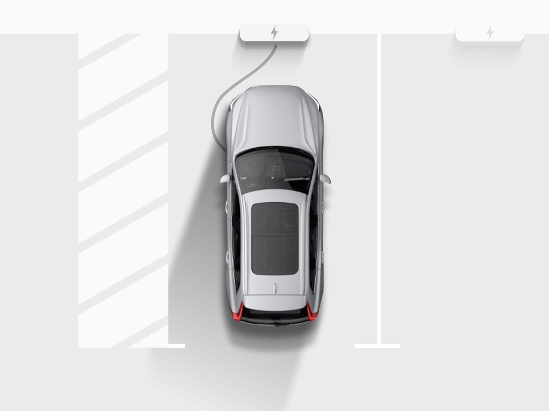 Digitāla attēla skats no augšas uz sudraba krāsas Volvo XC40 Recharge pilnība elektrisko apvidus automašīnu, kas pievienota uzlādes stacijai dzīvokļu mājas stāvvietas garāžā.