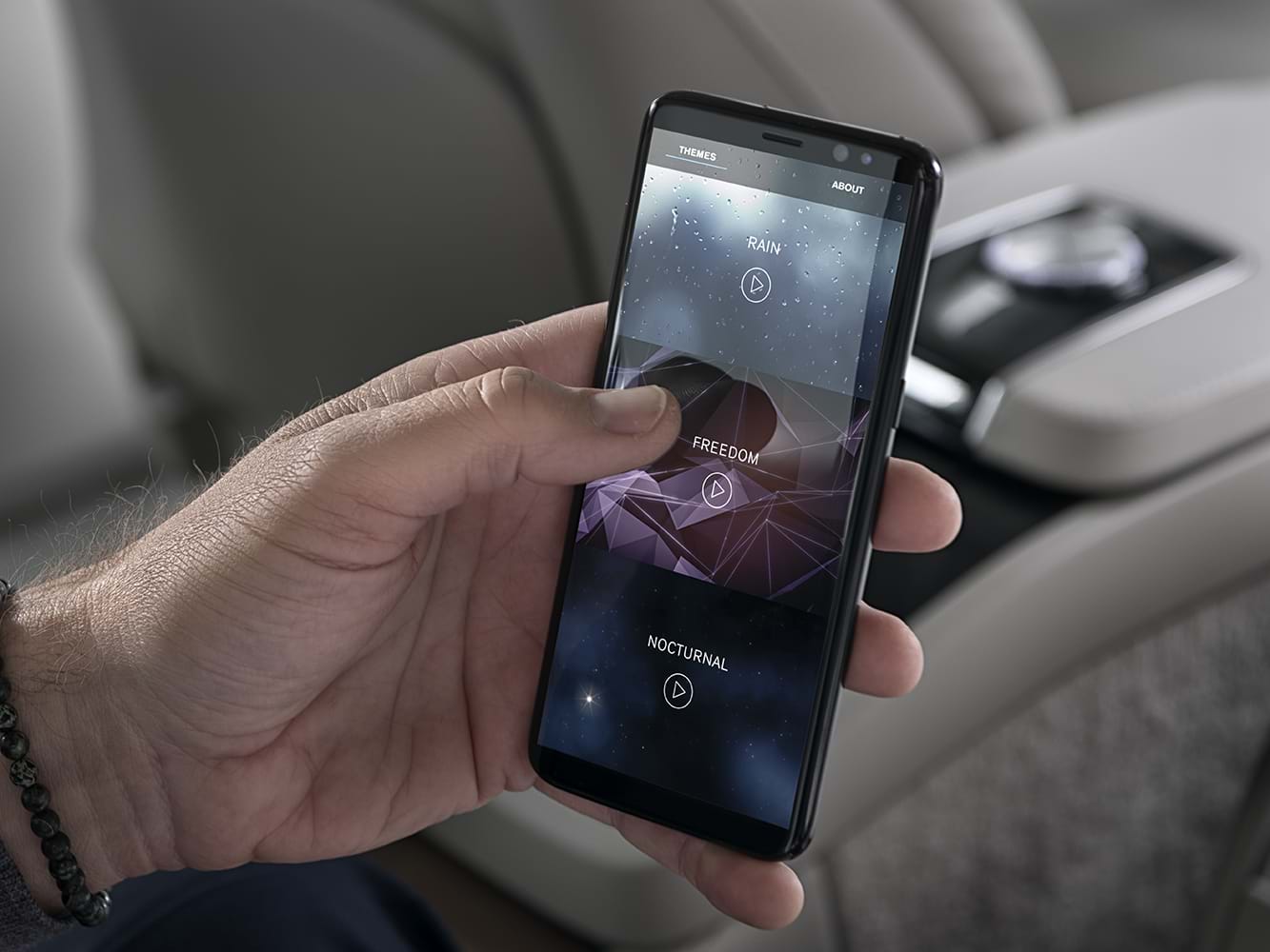 Una mano che seleziona una modalità Volvo Ambience Interior su uno smartphone