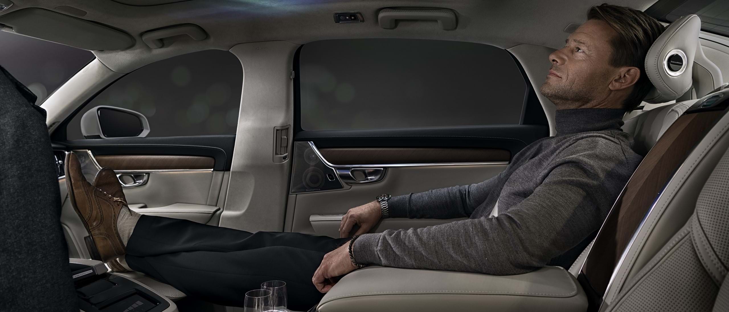 Një burrë i mbështetur në ndenjësen e pasme të një makine Volvo duke shijuar veçorinë Ambience Interior.
