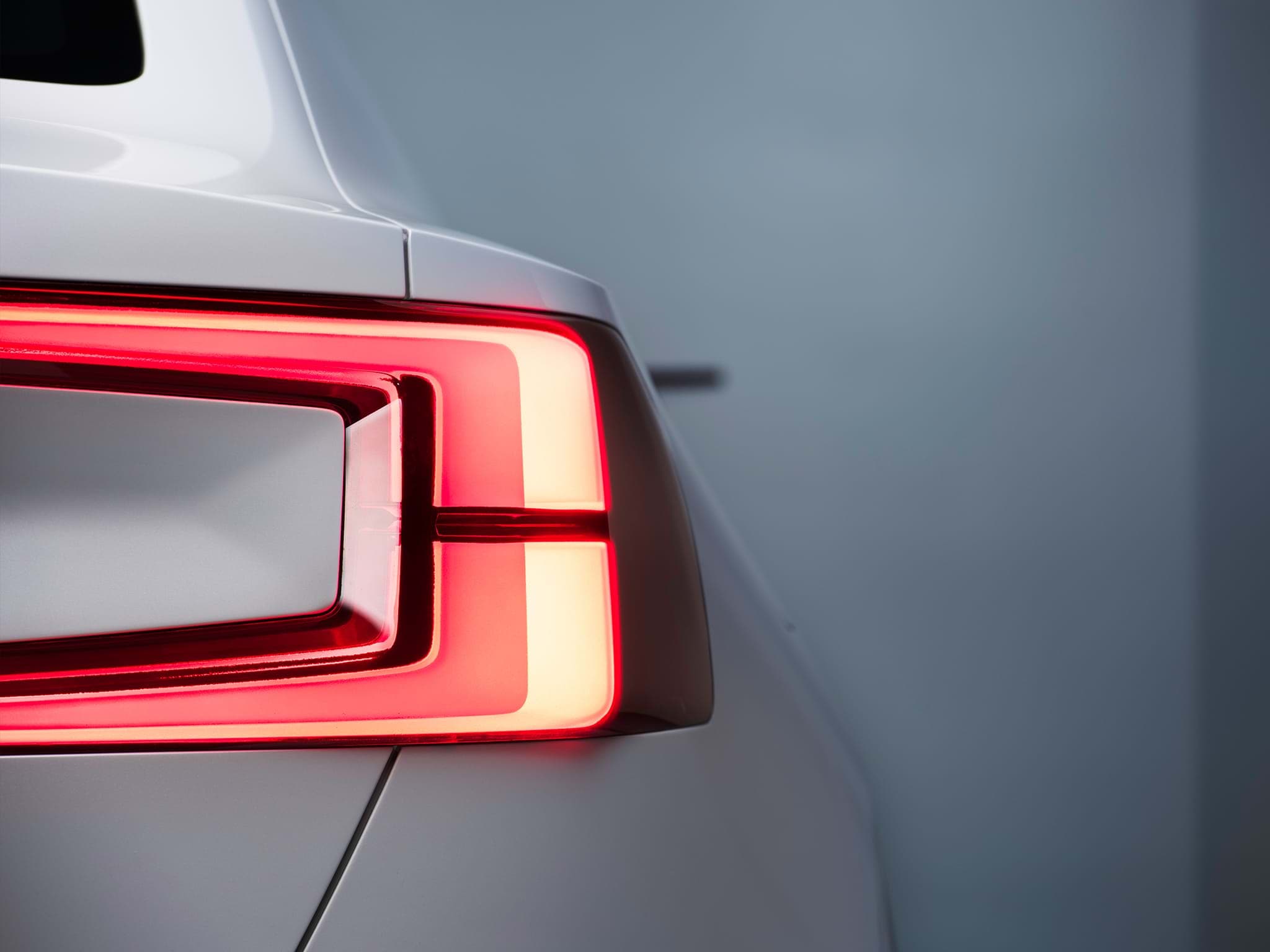 Vista parcial da traseira do carro sedan Volvo Concept 40 branco com luzes traseiras acesas