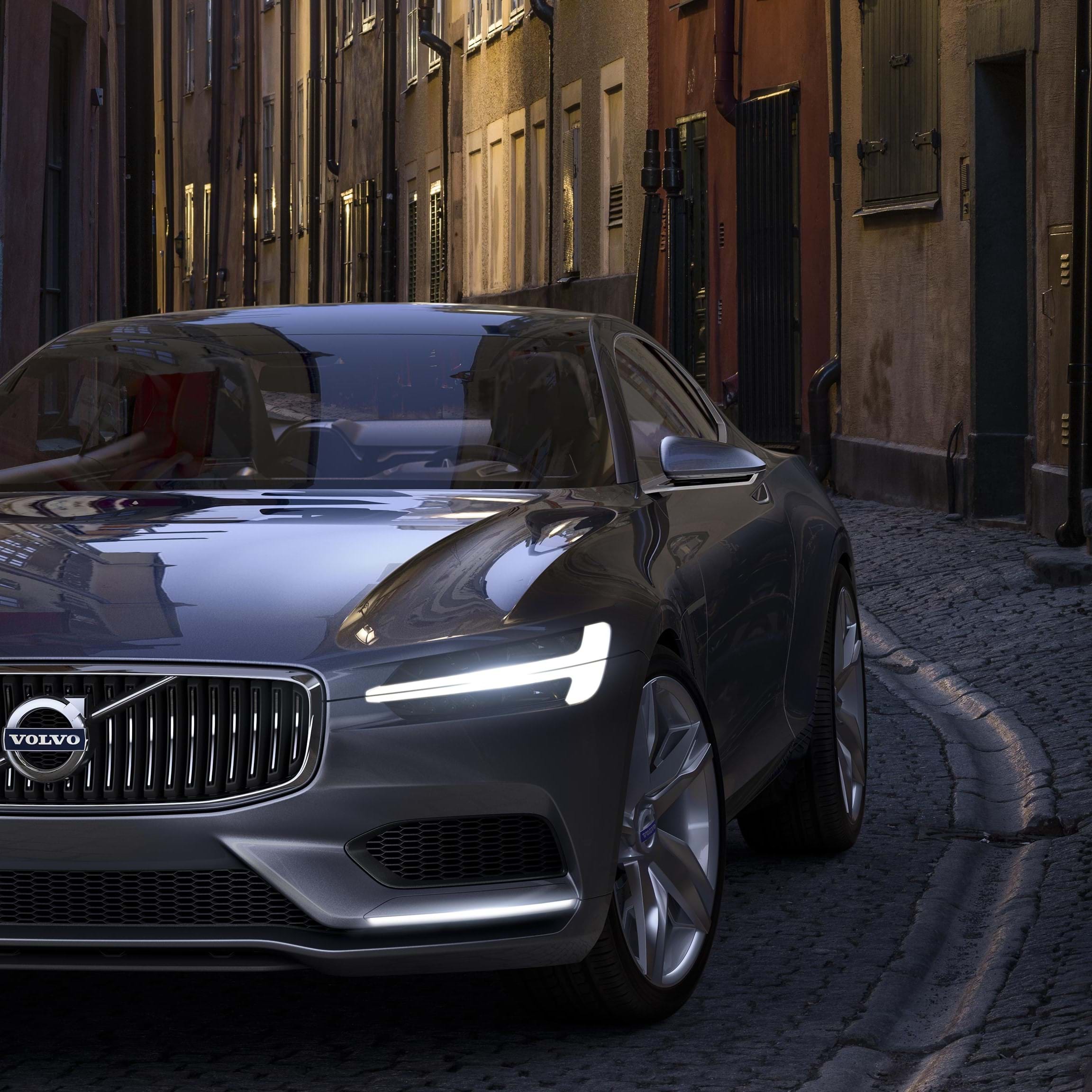 Een grijze Volvo Concept Coupé rijdt over een kasseiweg in de stad