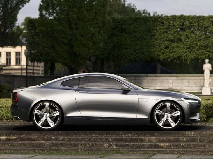 A silver Volvo Concept Coupe parked in front of a hedge and statue