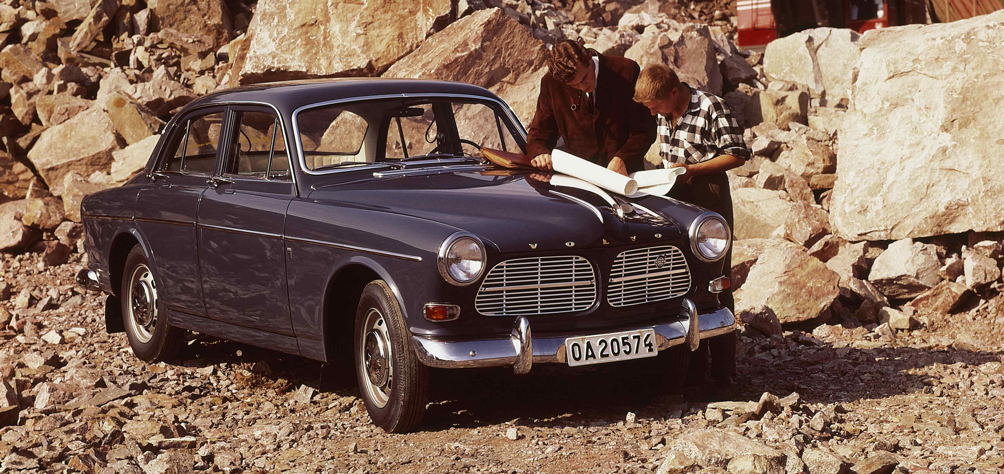 Two men look at a map on the bonnet of a Volvo P1200/P120 Amazon