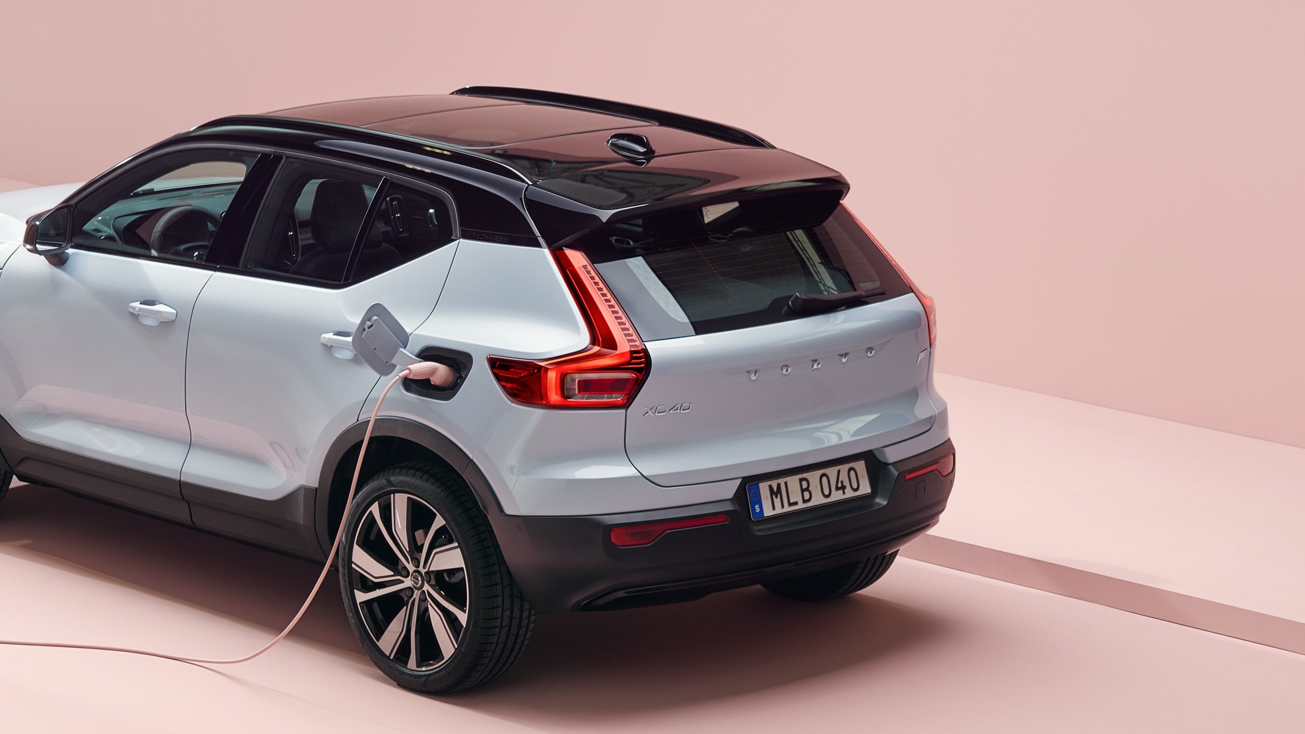 A grey Volvo XC40 Recharge, charging in a pink surrounding