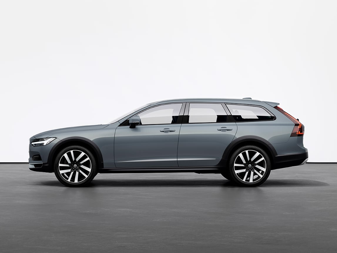 A mussel blue metallic Volvo V90 Cross Country Estate standing still on grey floor in a studio