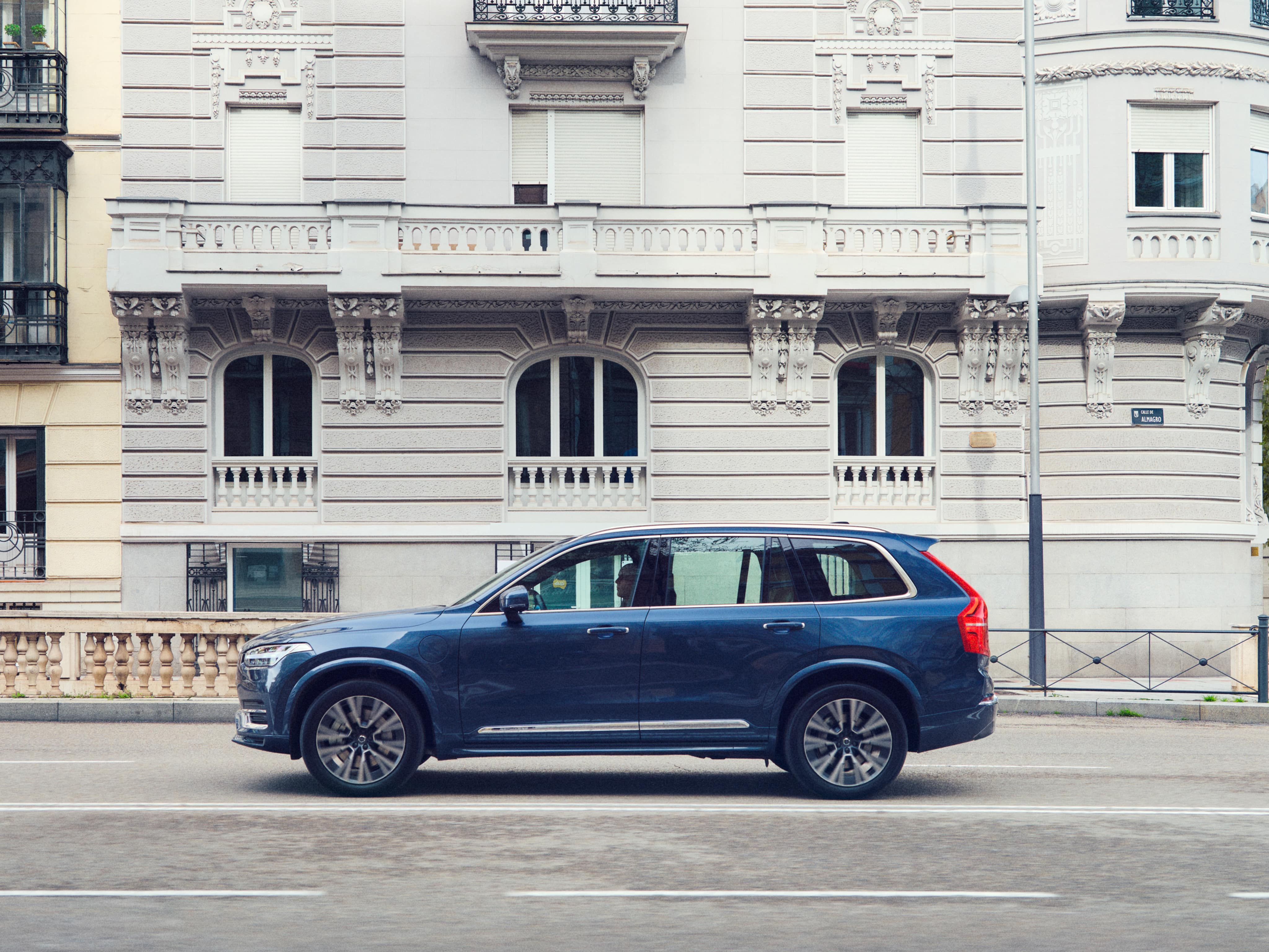 A Volvo XC90 Recharge plug-in hybrid parked in front of a building.