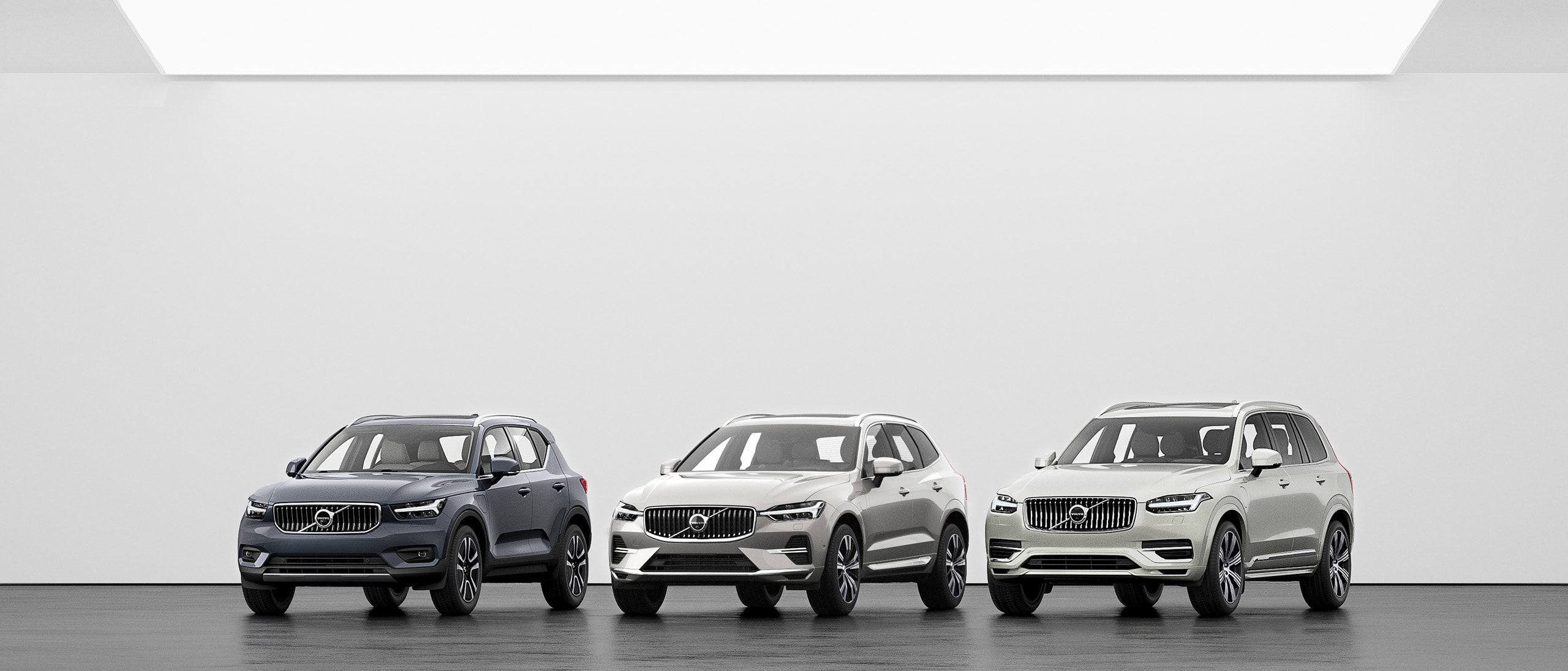 A lineup of Volvo SUVs, XC40, XC60 and XC90 on a grey floor.