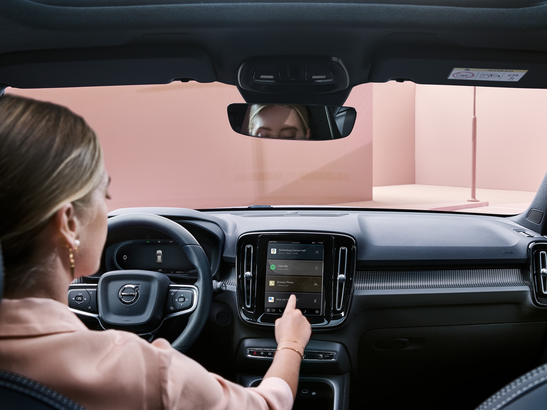 Seorang perempuan di dalam mobil Volvo XC40 Recharge, sedang menggunakan sistem konektivitas
