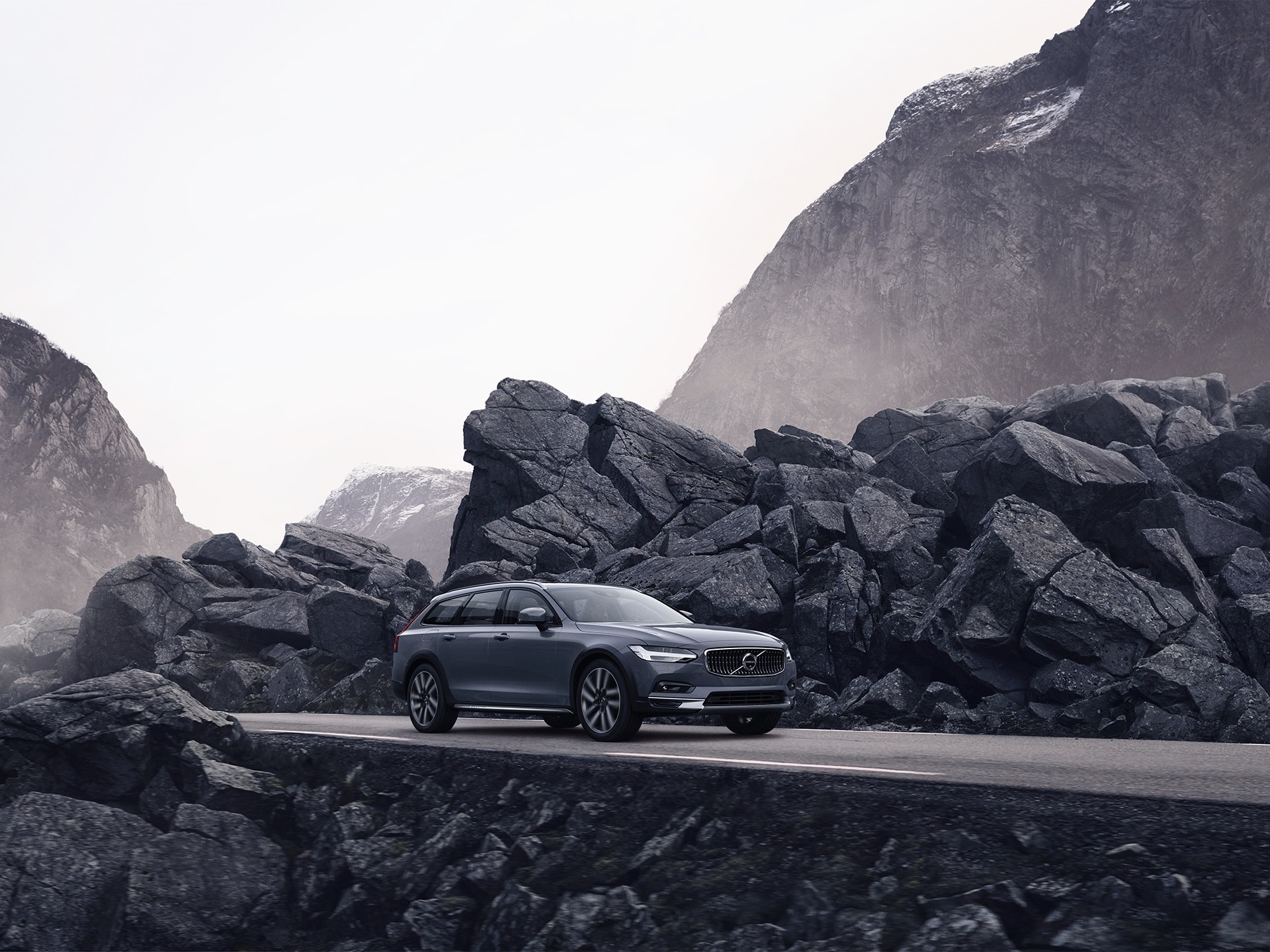 Volvo grise empruntant une route bordée de rochers