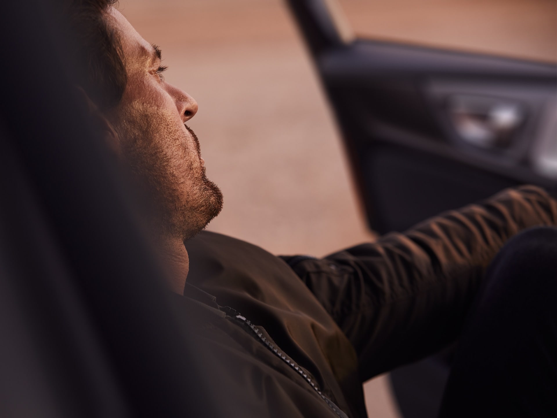 棕髮男子坐在 Volvo S60 內，陽光照映在他的臉上。