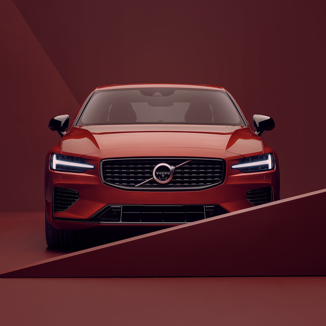 The front exterior of a red Volvo S60 Recharge in red surroundings.