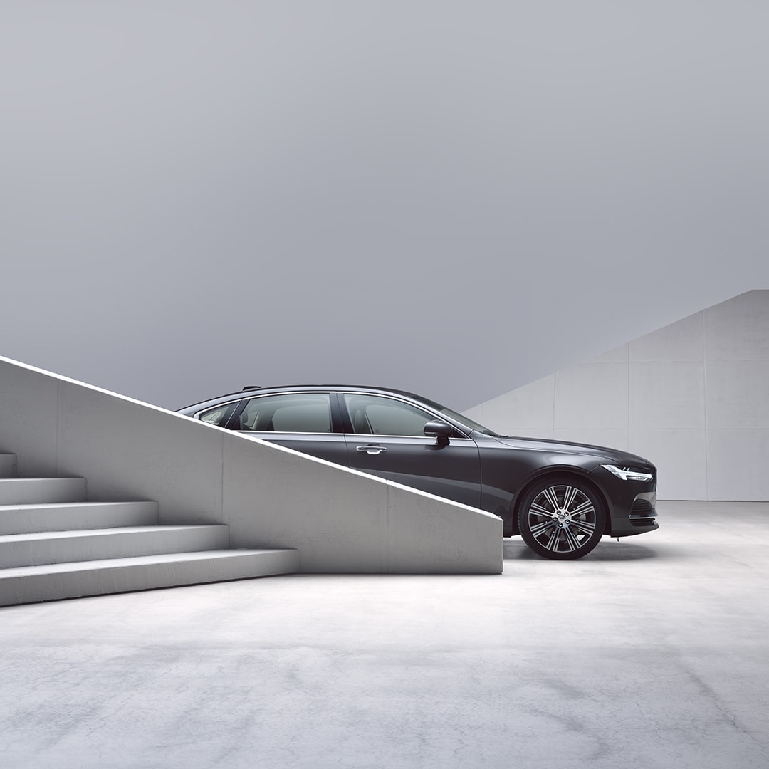 A Volvo S90 partially obscured by stairs.