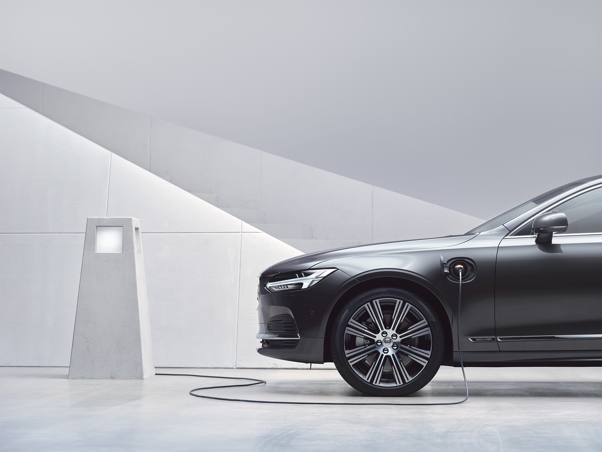 A Volvo S90 Recharge gets charged at a charging station.