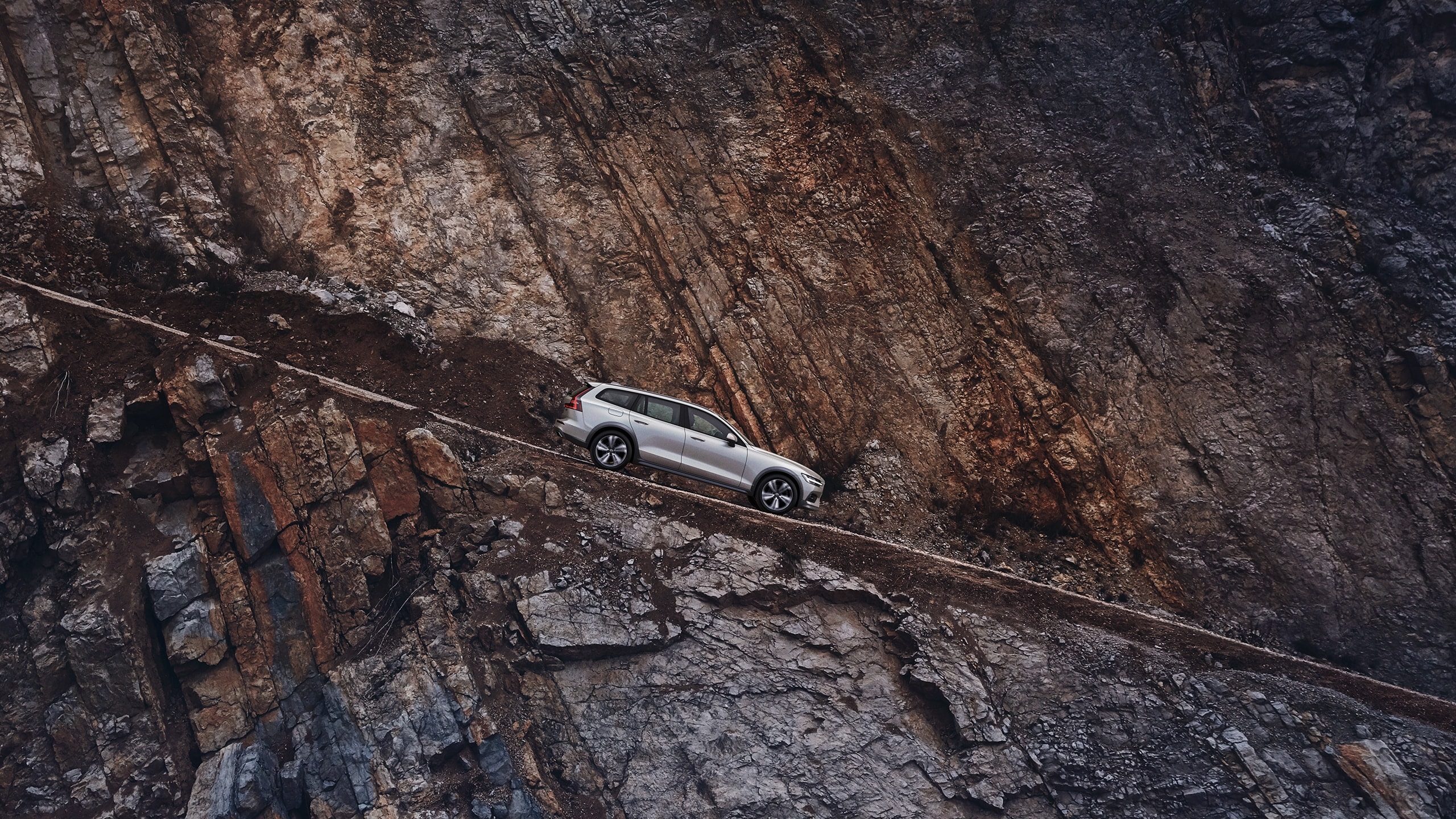 A Volvo V60 Cross Country drives down a mountain road.