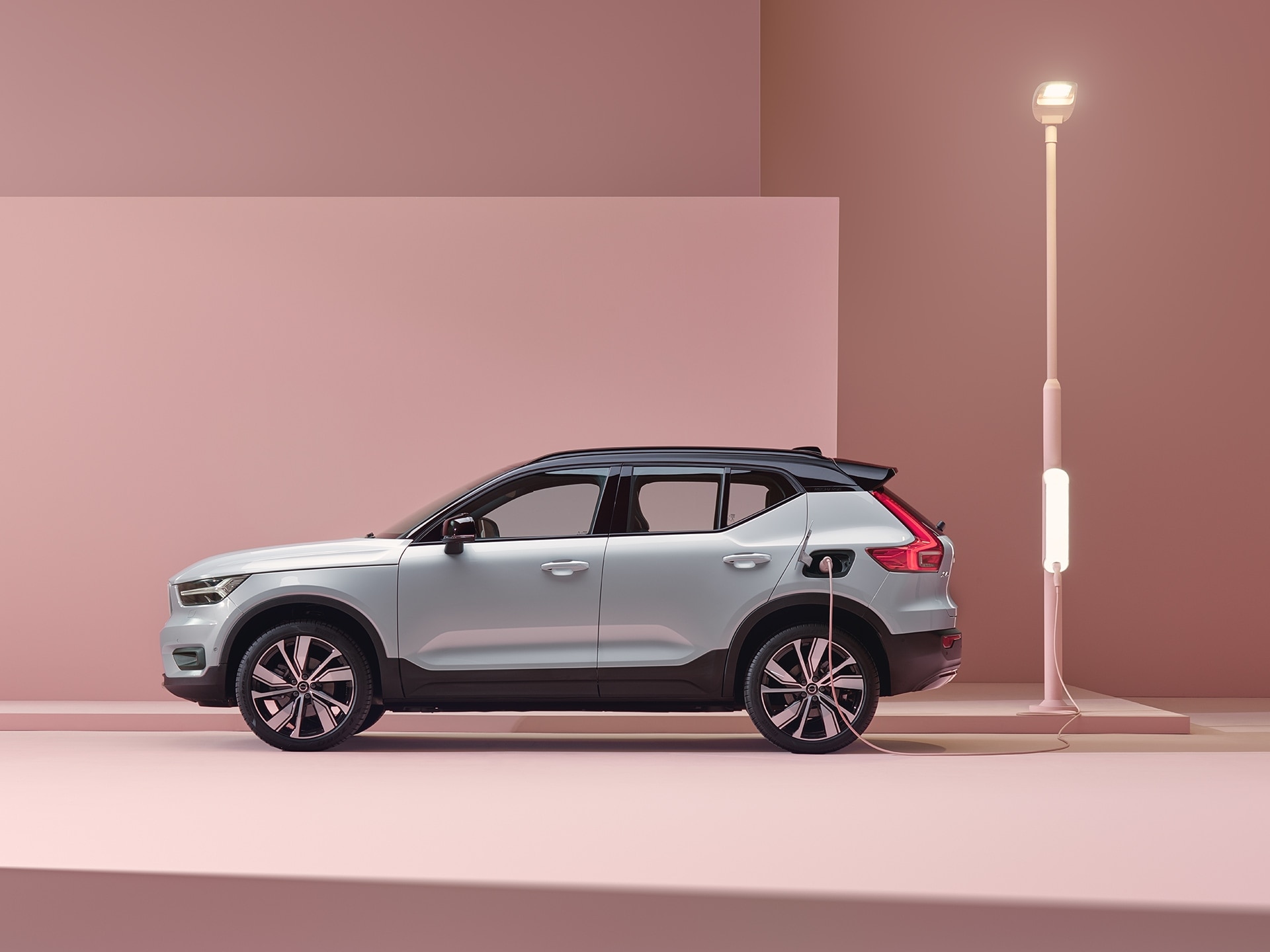 A glacier silver Volvo XC40 Recharge electric SUV charged in a pink city.