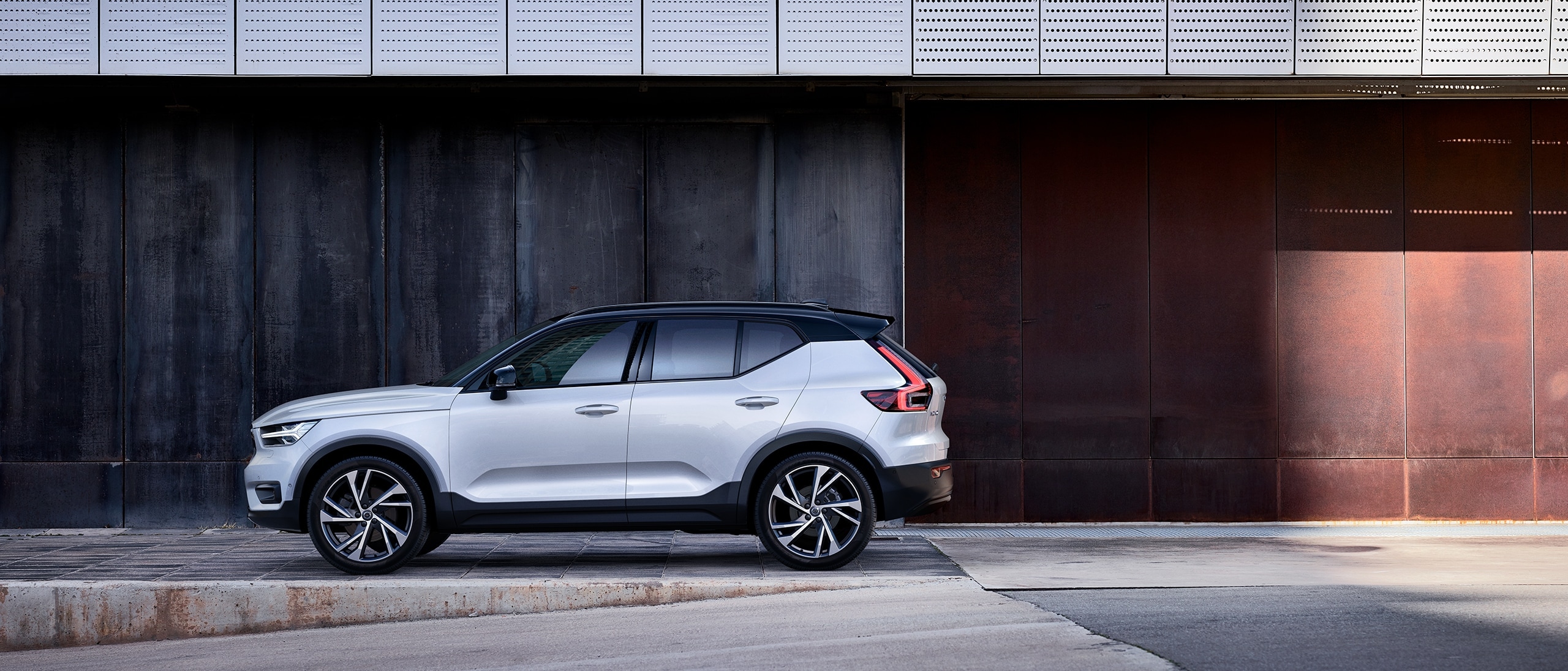 A white XC40 is parked outside a building.