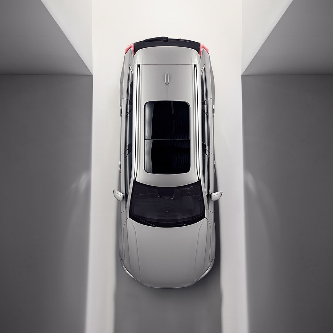 Açıq və qaldırılan panoramik dam örtüyü ilə Volvo XC90 avtomobilinin yuxarıdan görünüşü.