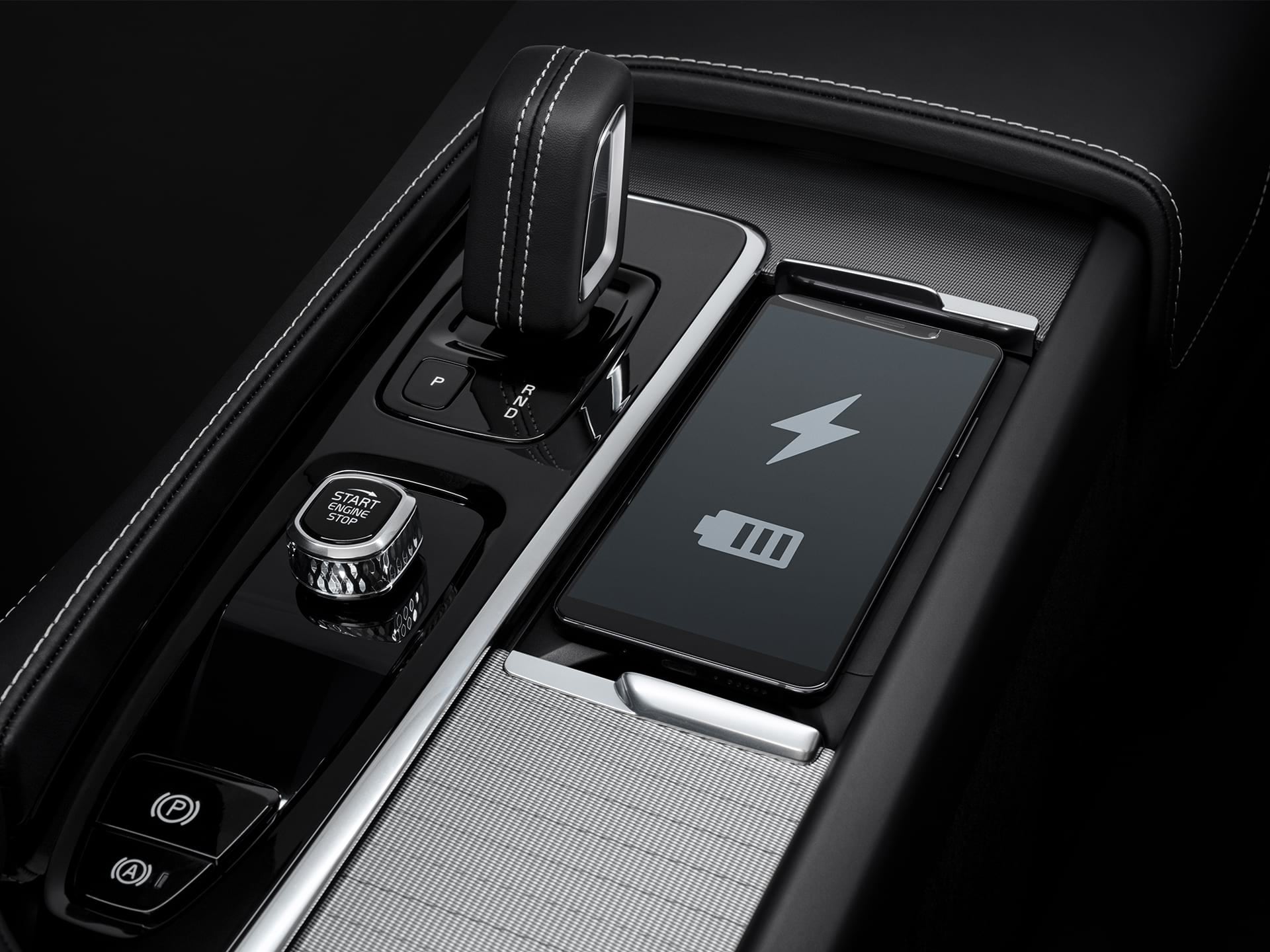 Dedicated smartphone storage space with wireless fast-charging for compatible devices inside a Volvo XC90.