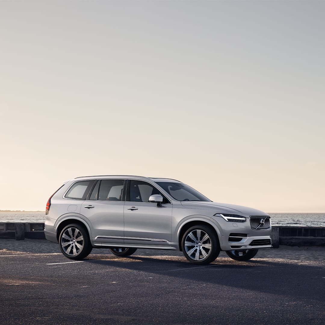 A Volvo XC90 Recharge parked along a road by the sea.