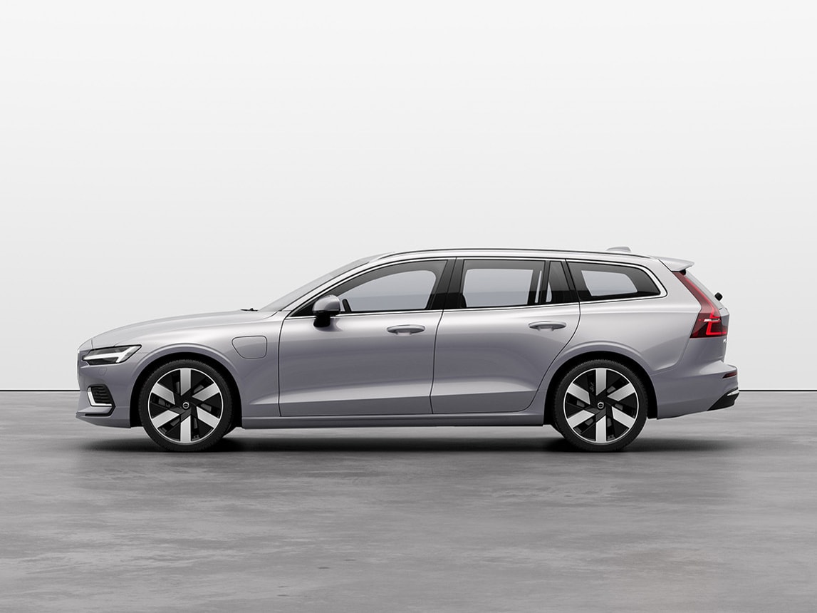 A silver Volvo V60 Recharge standing still on grey floor in a studio.