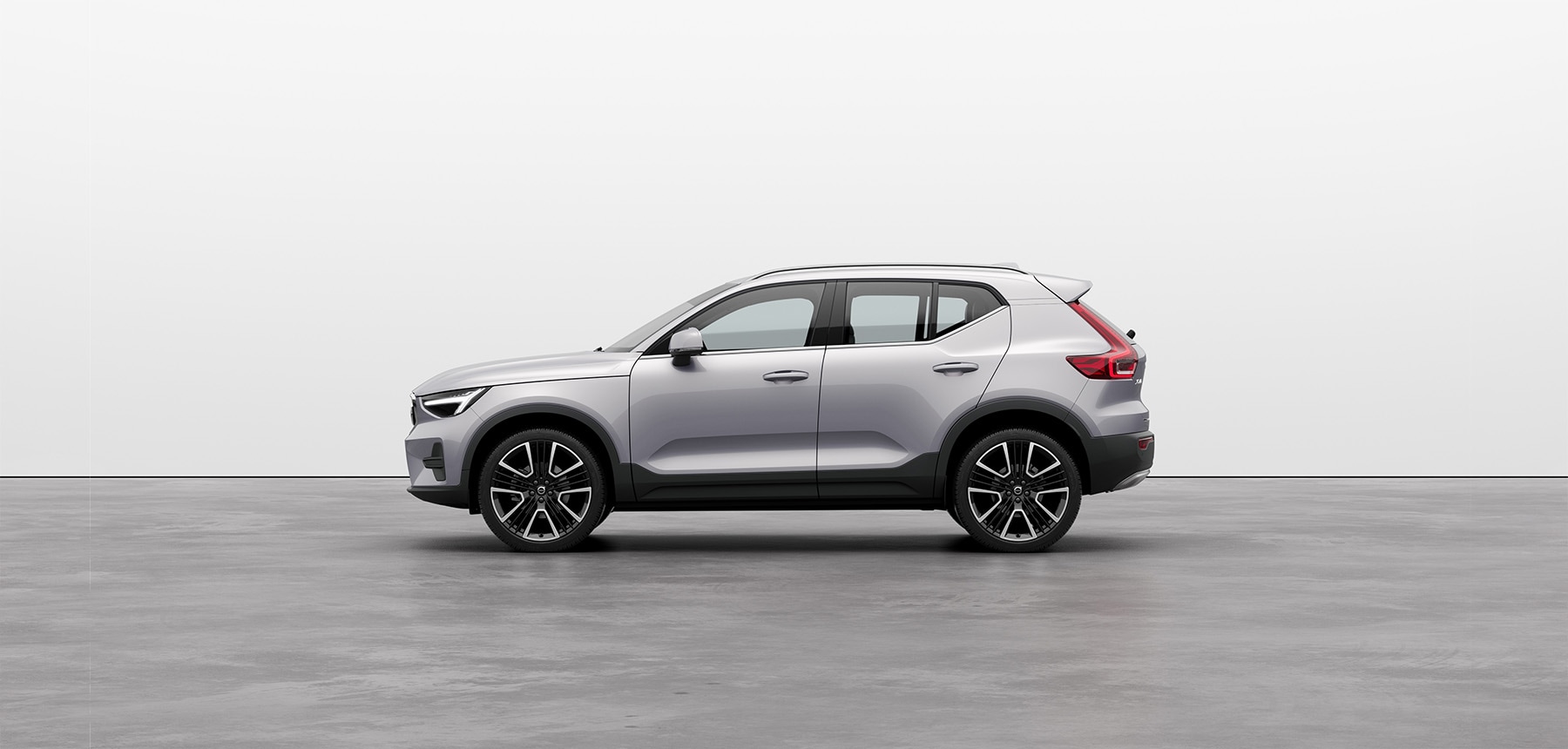 A silver Volvo XC40 compact SUV standing still on grey floor in a studio