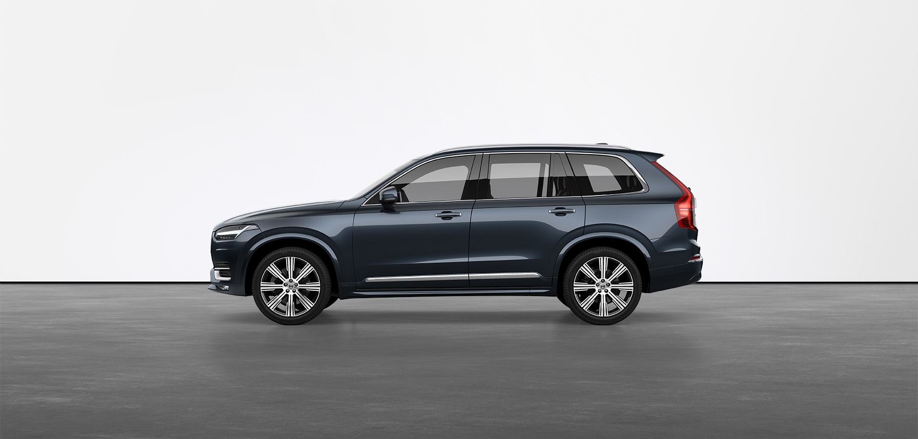 A silver Volvo XC90 compact SUV standing still on grey floor in a studio
