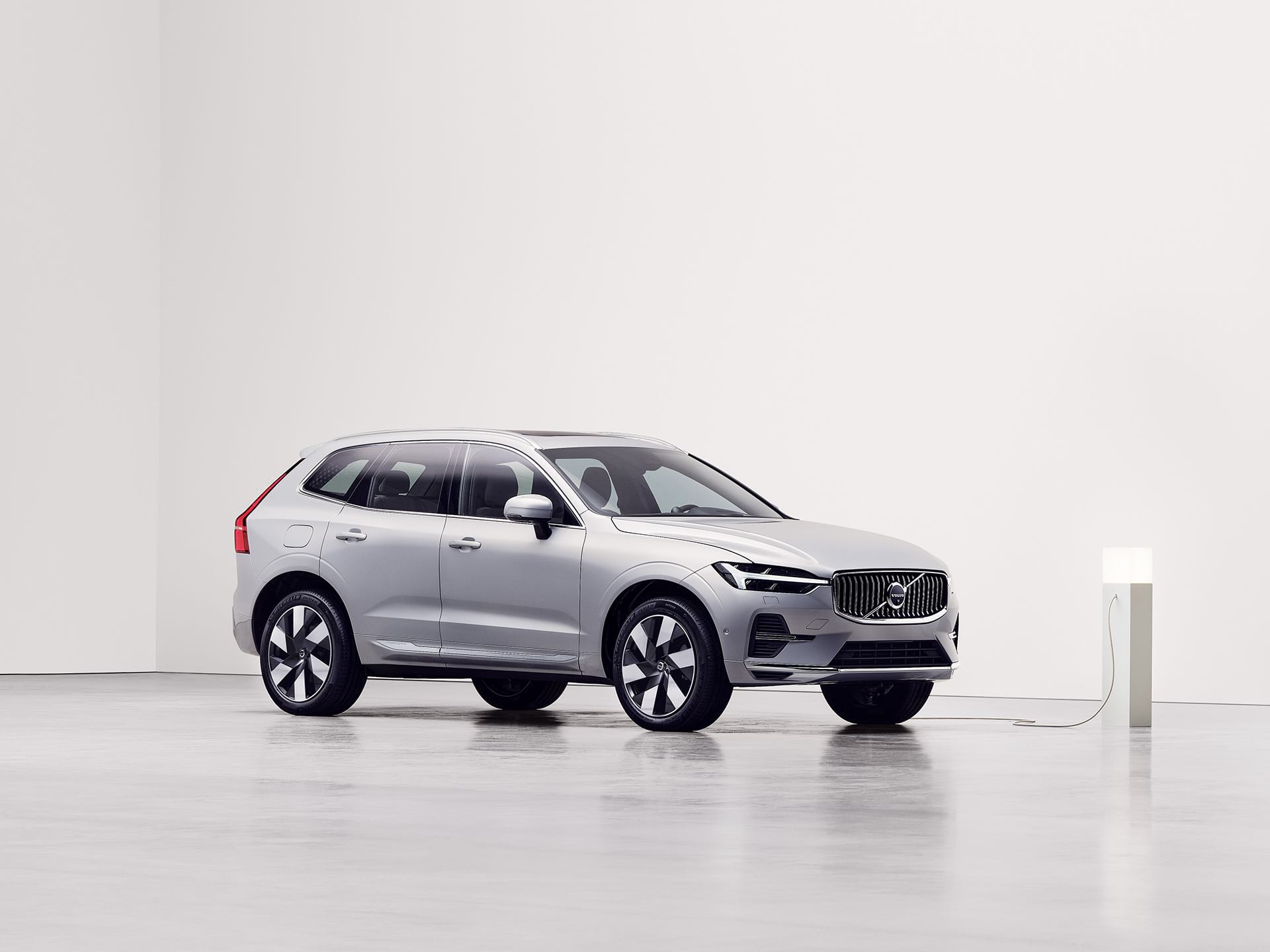 Side view of a plug-in hybrid Volvo SUV being charged at charging station. 