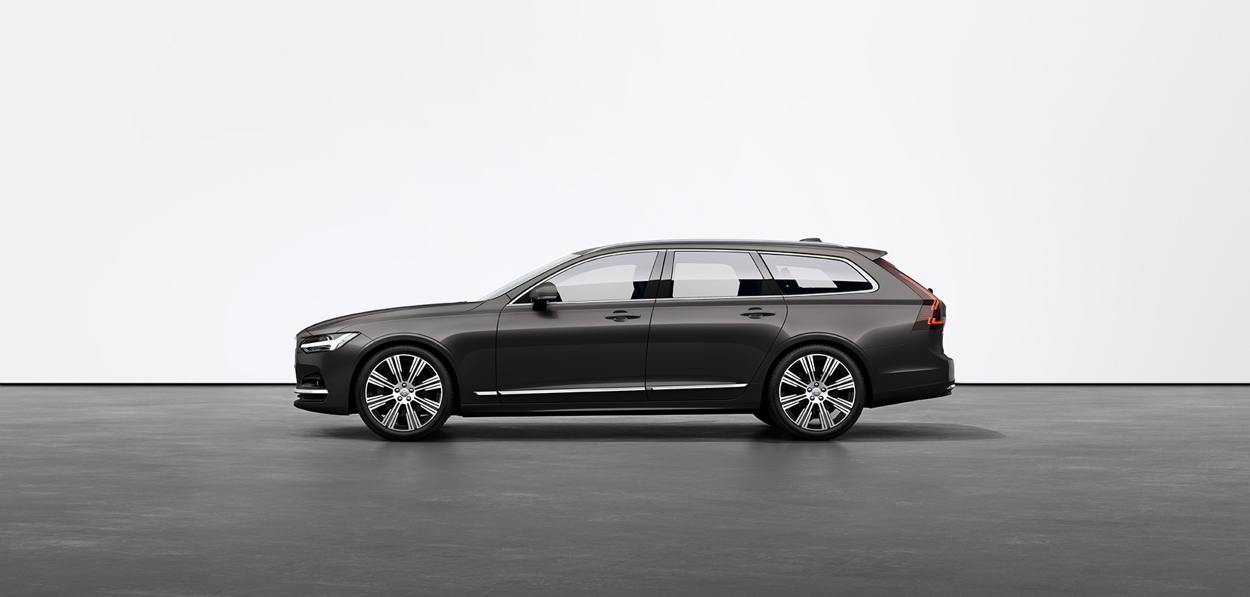 Een grijze Volvo V90 break staat stil in een fotostudio met een grijze ondergrond.
