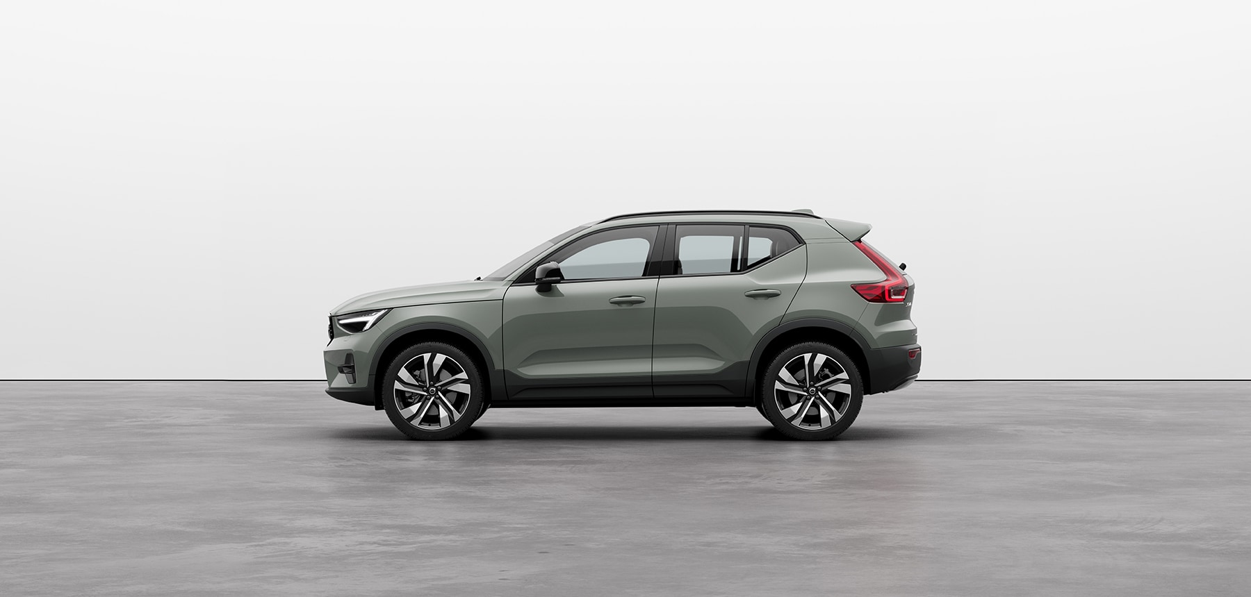 A silver Volvo XC40 compact SUV standing still on grey floor in a studio
