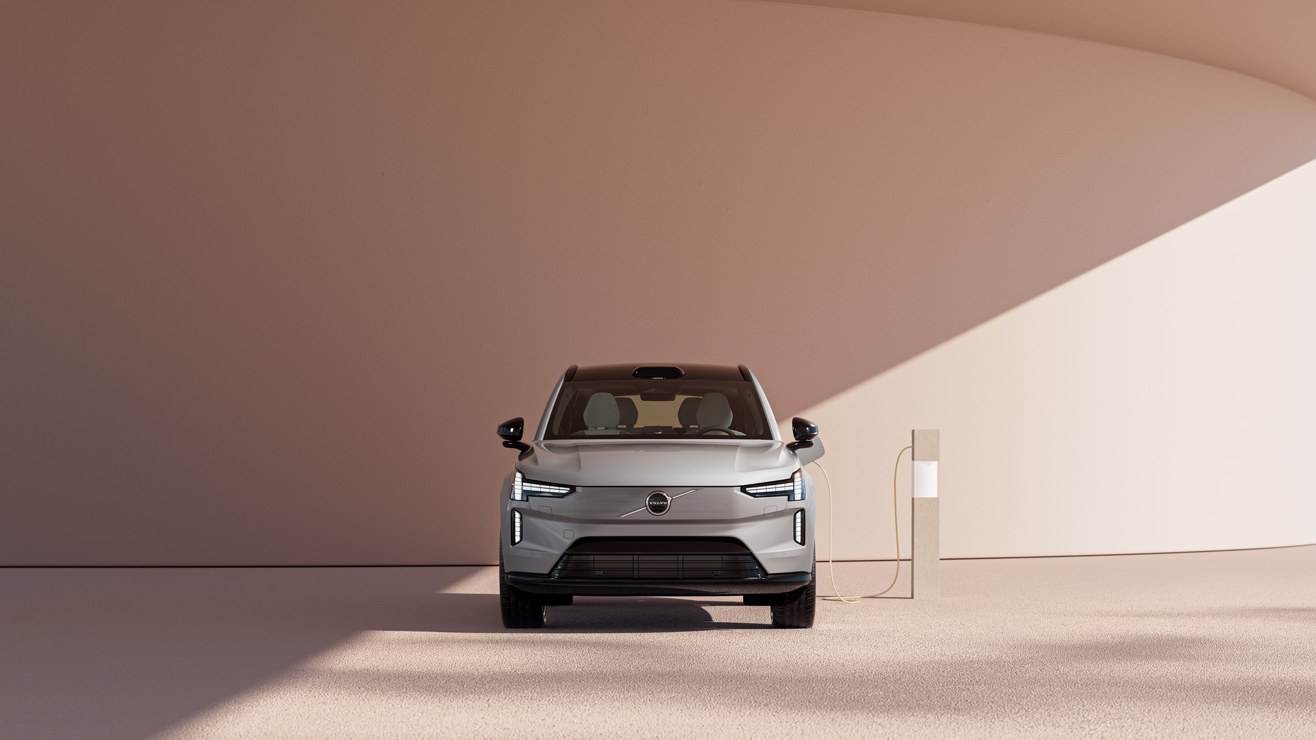 מבט מלפנים על רכב הפנאי-שטח החשמלי החדש של וולוו EX90 בטעינה, על דיונה חולית