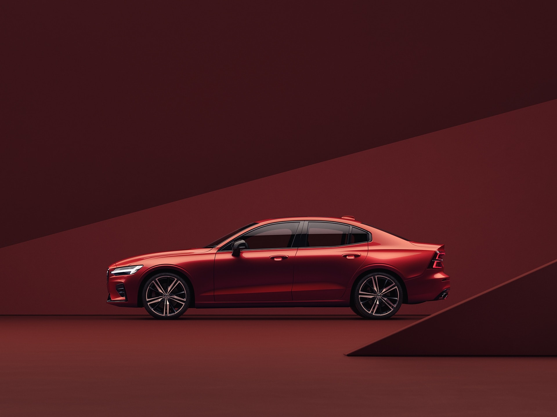 Volvo S60 красного цвета, припаркованный на красном фоне