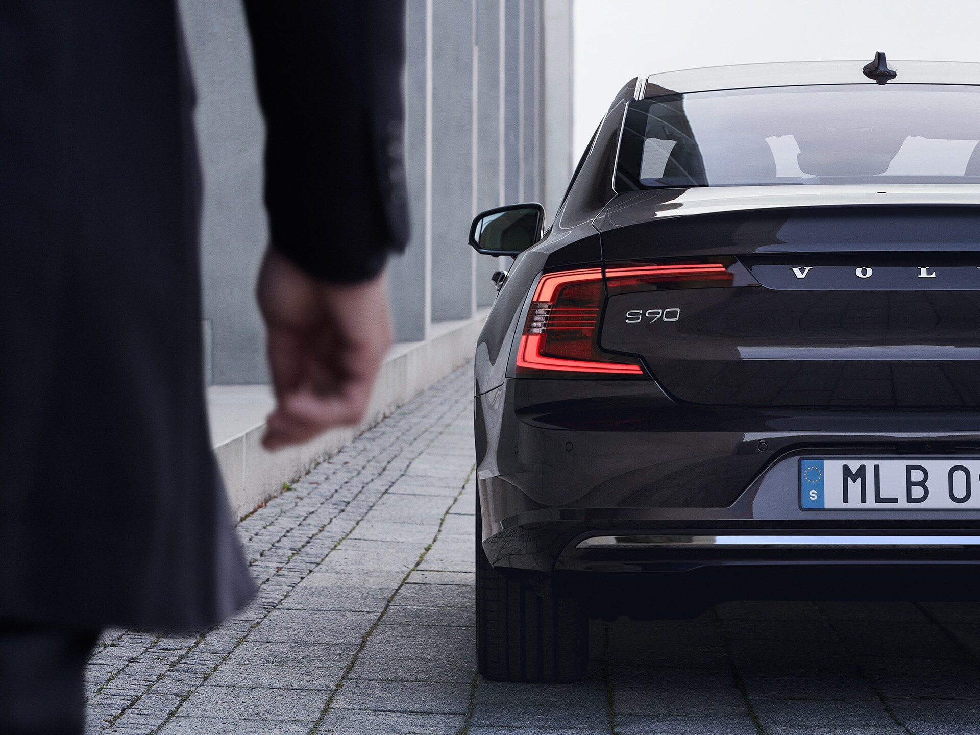 A man walks towards a black Volvo S90 Recharge