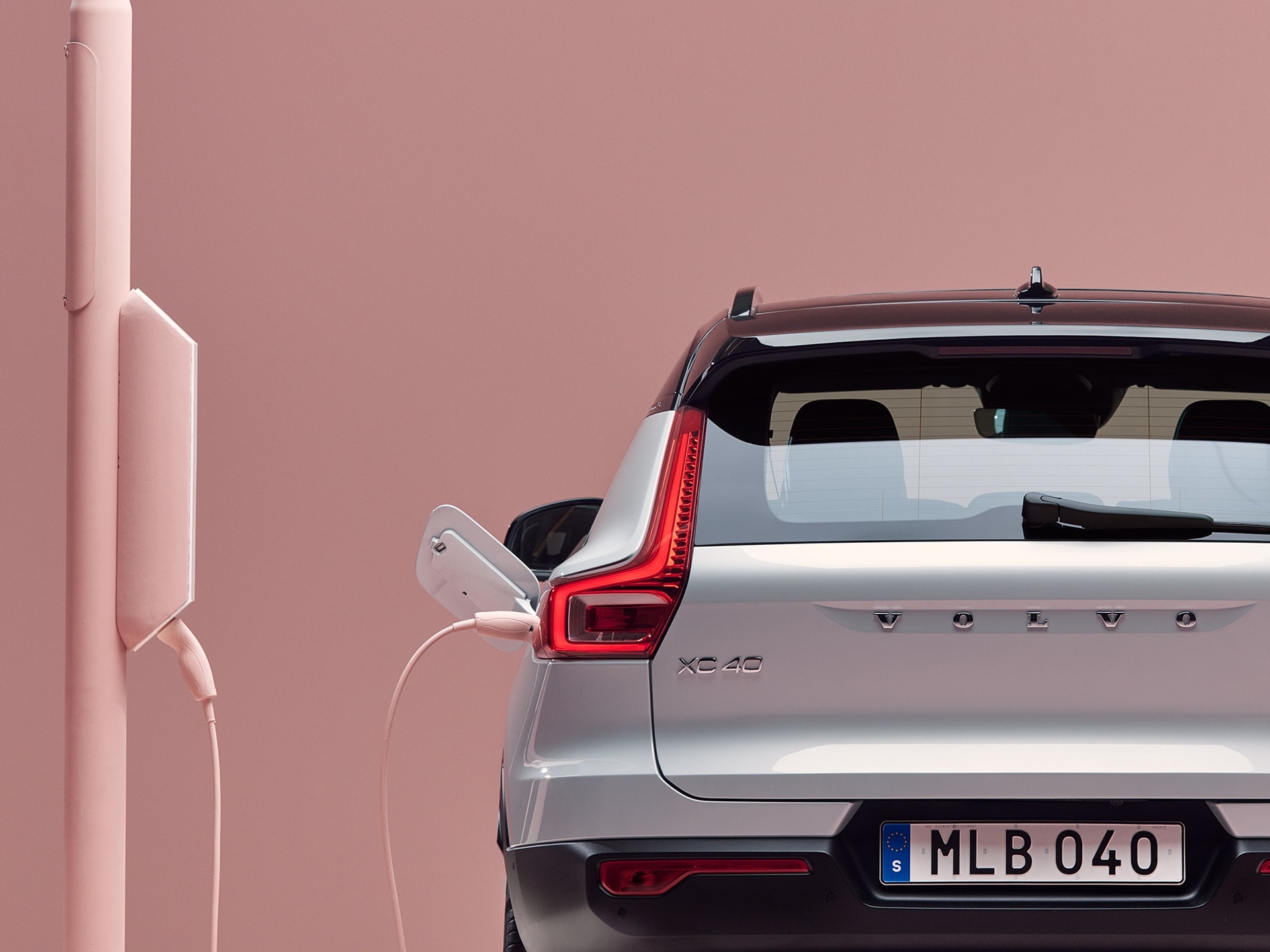 View from the rear of a Volvo XC40 Recharge Pure Electric SUV plugged in to a charging box installed on a light post.