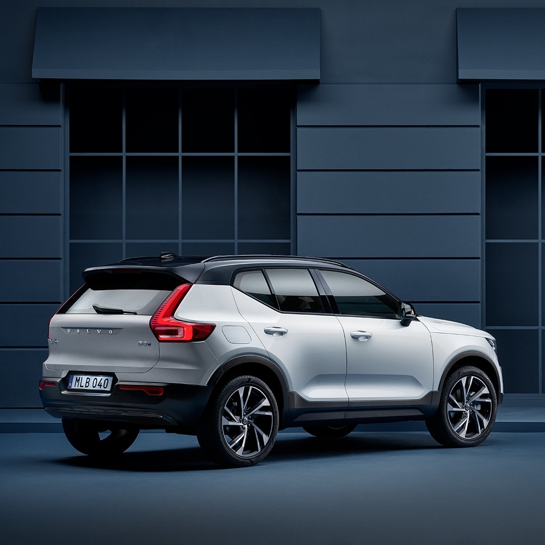 A Volvo XC40 Recharge plug in hybrid stands parked along a blue facade