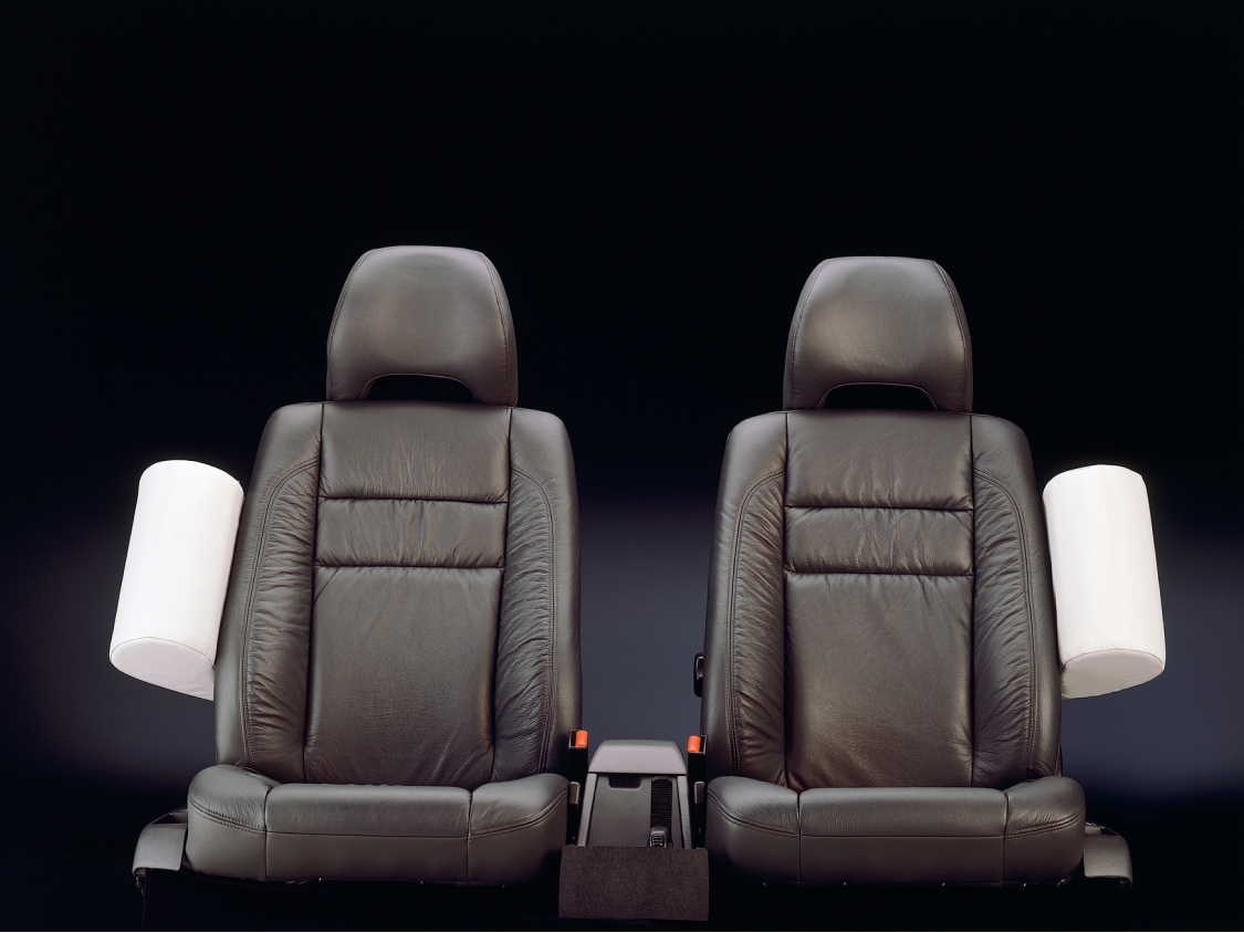 Two black car seats with one white side-impact torso airbag on each side.