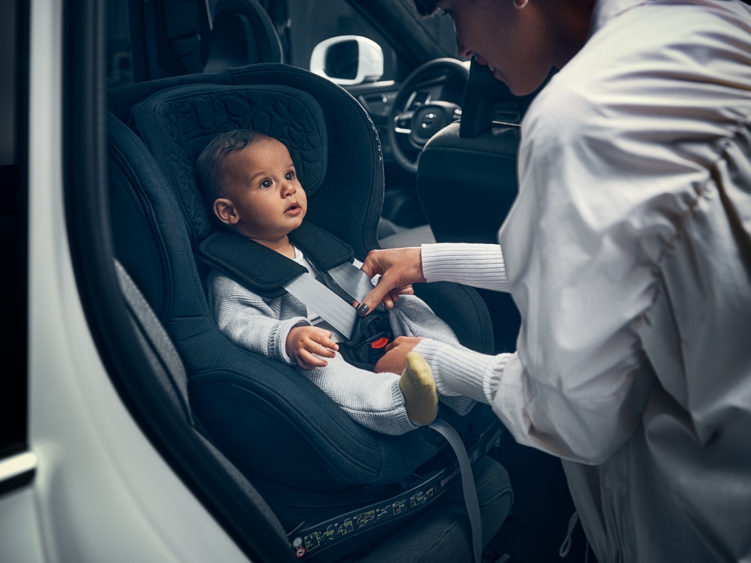 A woman belting a child to the car seat.