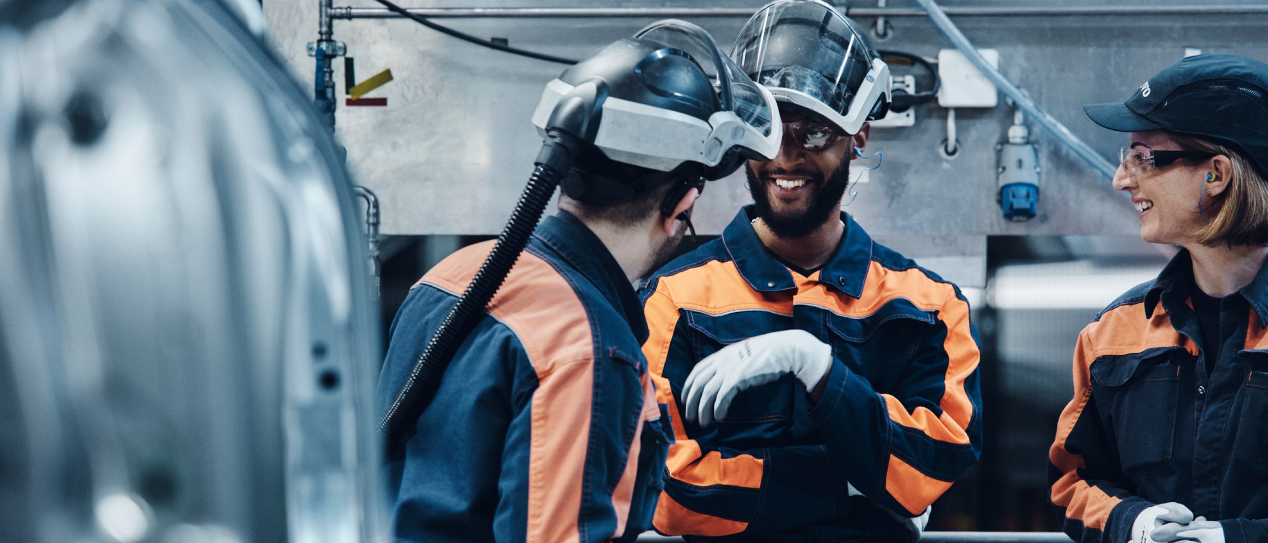 Three people having a chat wearing safety gear and work overalls.