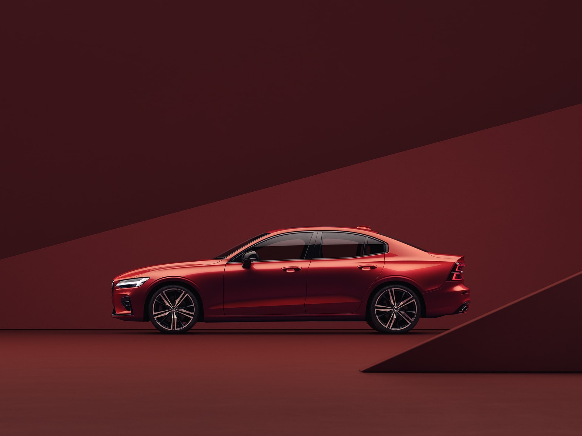 Um sedan Volvo S60 em vermelho, estacionado num ambiente da mesma tonalidade.