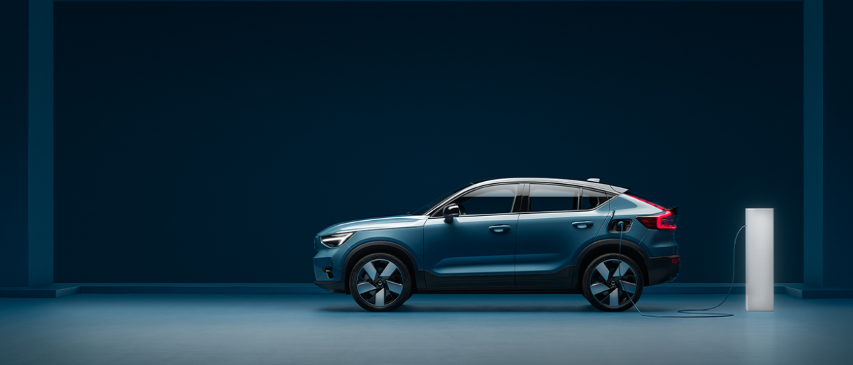 Side profile view of a Volvo C40 that’s charging inside a blue room